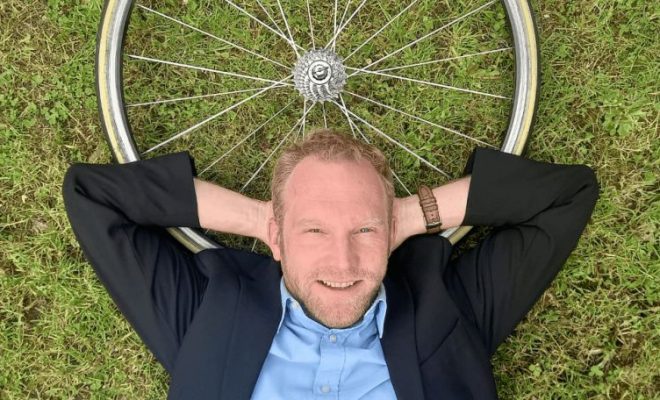 Cyril Fragniere coucher dans l'herbe avec une roue de vélo comme oreiller