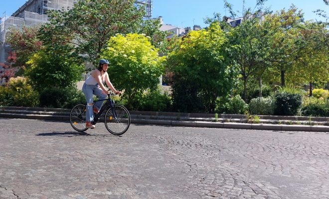 Aides à l'achat d'un vélo, femme sur vélo urbain électrique sur une route pavée dans Paris