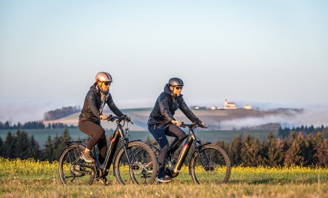 Un homme et une femme sur des vélos à assistance électrique de la marque italienne Malaguti en pleine campagne