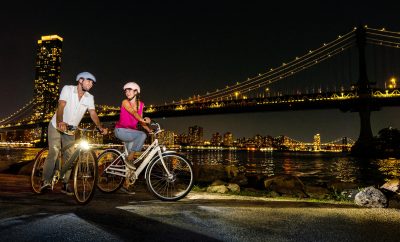 Un homme et une femme roulant de nuit sur des vélos électriques Electra