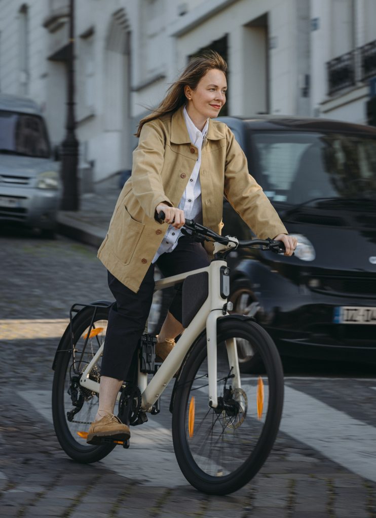femme roulant sur un vélo Lemmo de couleur crème dans les rues d'une ville