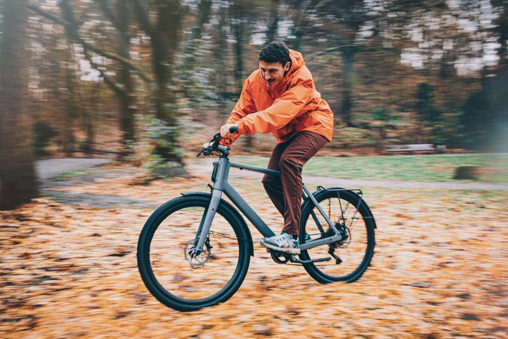 Homme au guidon d'un vélo Lemmo roulant dans des feuilles mortes