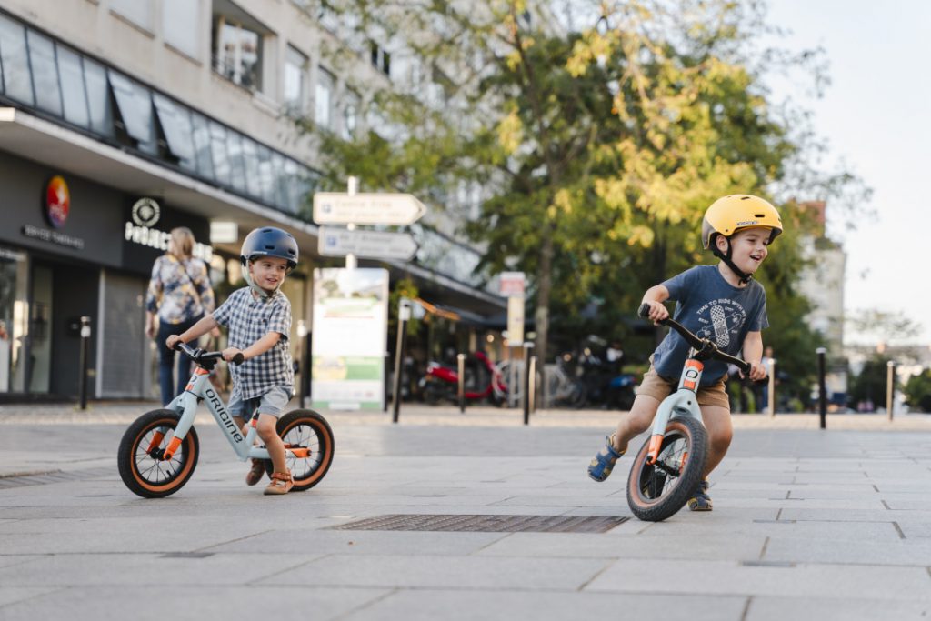 deux enfants roulant sur draisienne Origine Cycles en ville